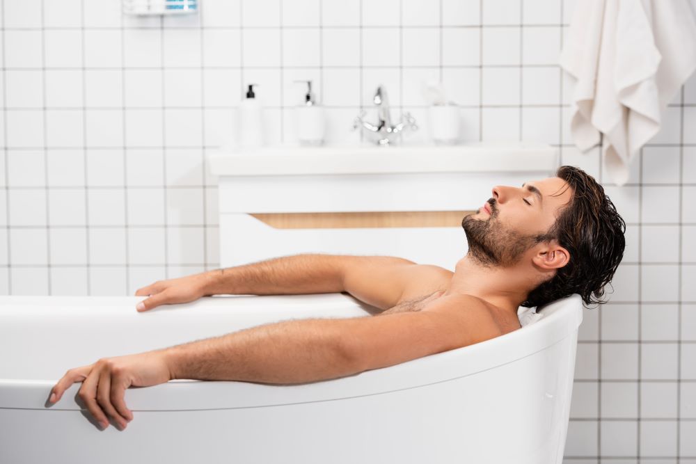 Attractive man relaxes in the bath tub. The Healing Power of Sensual Touch: A Journey into the Calming Depths of the Nervous System,