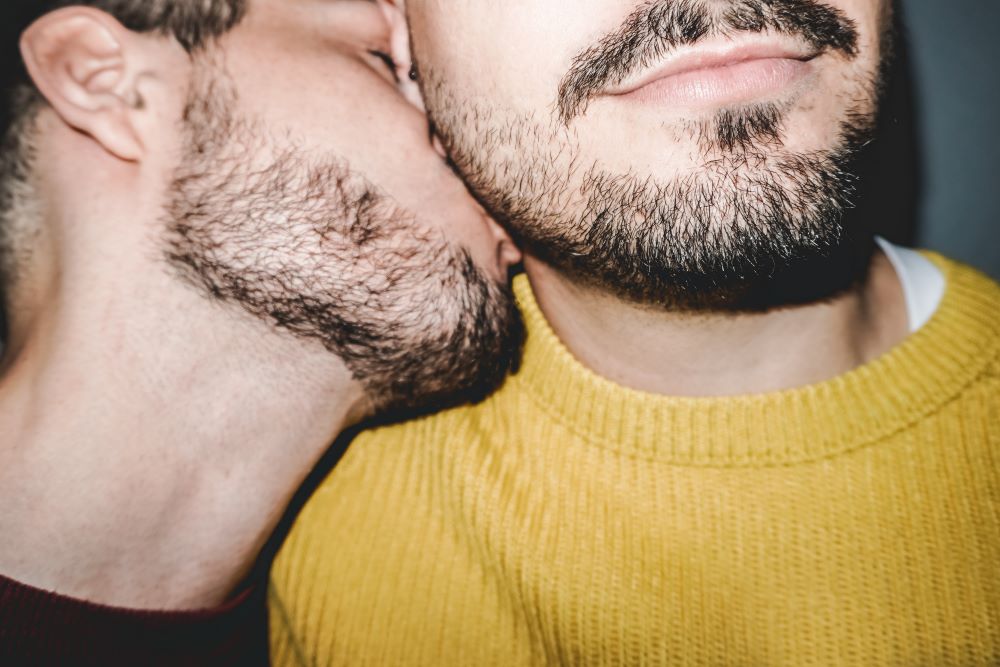 Man kisses his male partner's ear and neck in a sensual and erotic way as one of the 5 erogenous zones to make him melt.