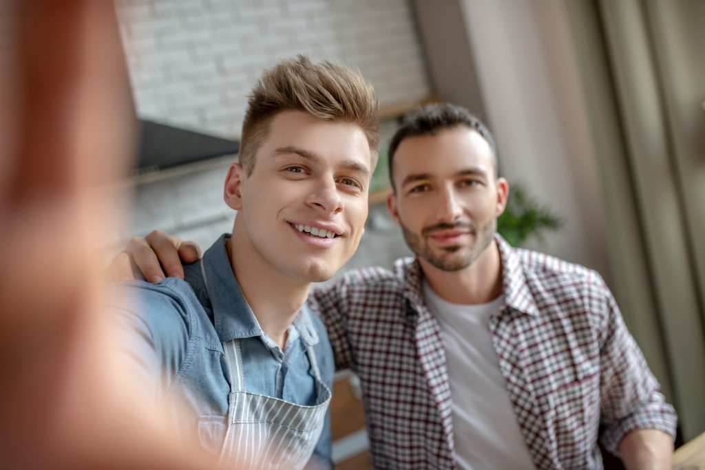 Two men in a fun embrace and looking at the camera. Embracing Fluidity: Male Sexuality, Cultural Shifts, and the Power of Erotic Massage