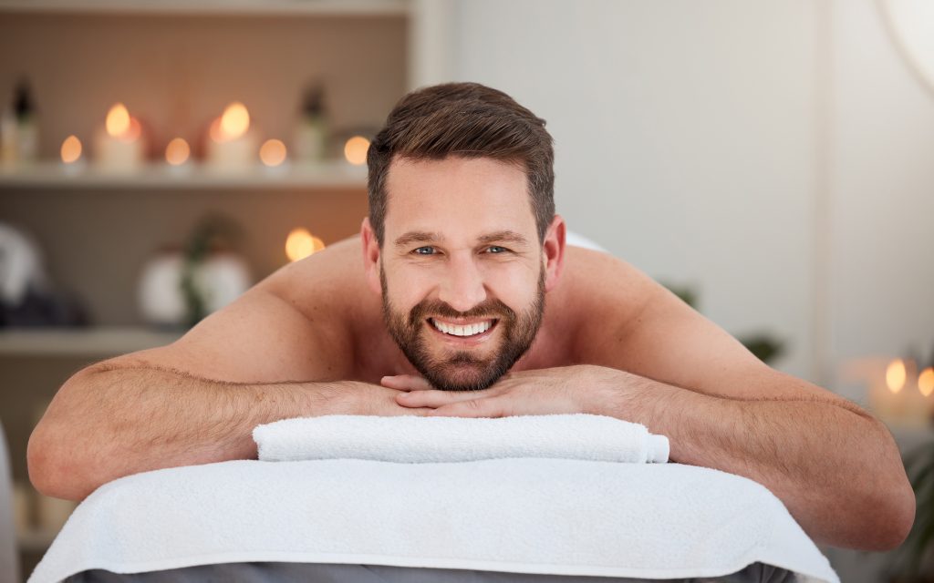 Happy man laying on a massage table. Deep Healing from the Transformative Power of Male Sensual Erotic Massage
