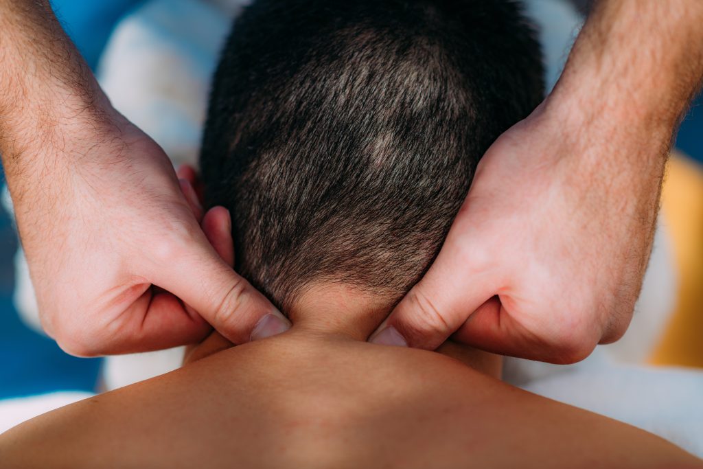 Male masseur massages his male client applying pressure at the neck region